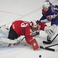 Švýcarský brankář Leonardo Genoni zasahuje před Loganem Cooleym.