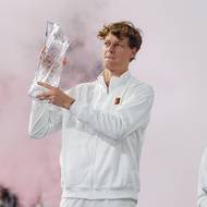 Jannik Sinner pózuje s trofejí pro vítěze turnaje v Miami, v pozadí stojí smutný Jiří Lehečka.