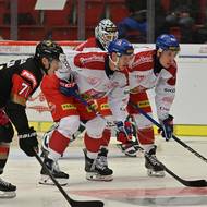 Hráči čekají před gólmanem Petrem Kváčou, než sudí hodí puk zpět do hry.