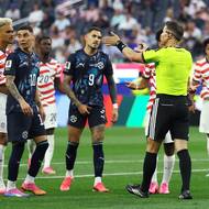 Nizozemský sudí Danny Makkelie signalizuje fotbalistům USA a Paraguaye, že komunikuje s kolegou u videa.
